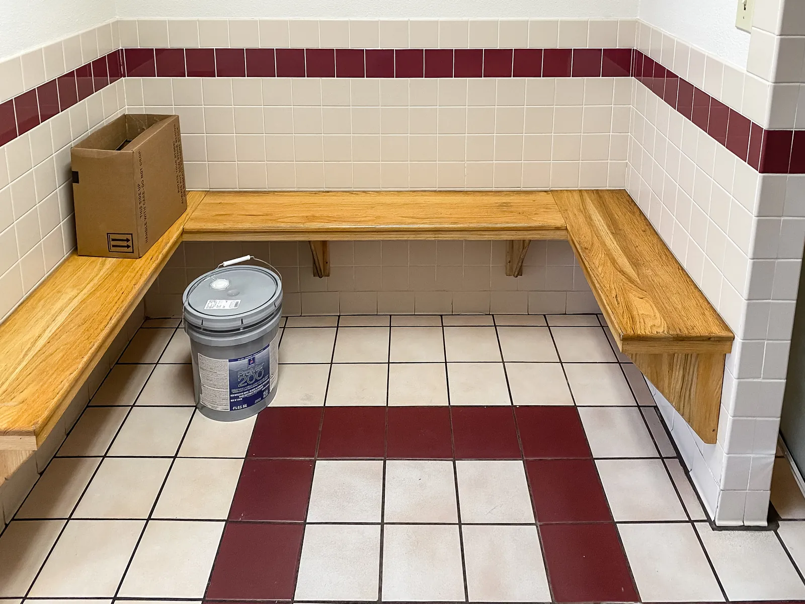 Austin Country Club locker room showers in maroon and white tile, before