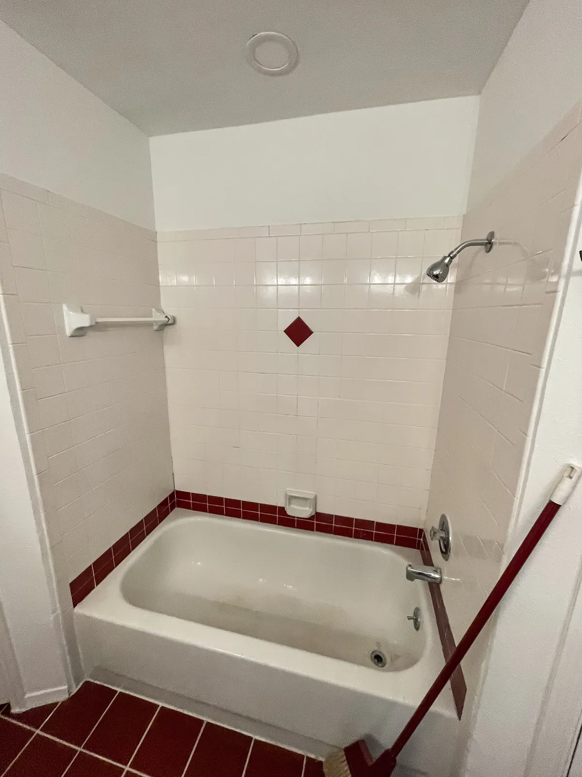Bathroom with maroon accent tile, tub and tile floor before refinishing