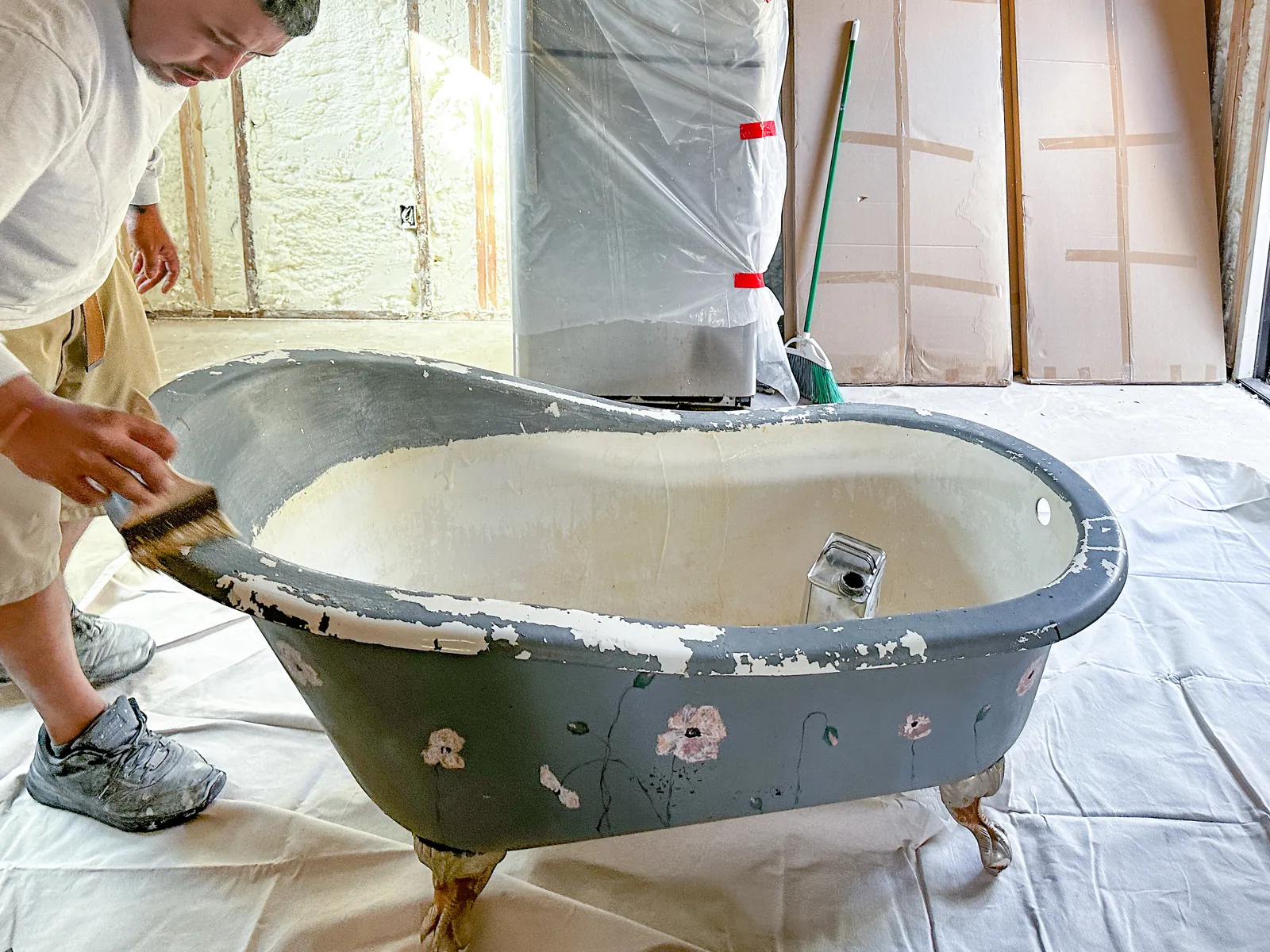 Technician stripping the old finish from a clawfoot tub
