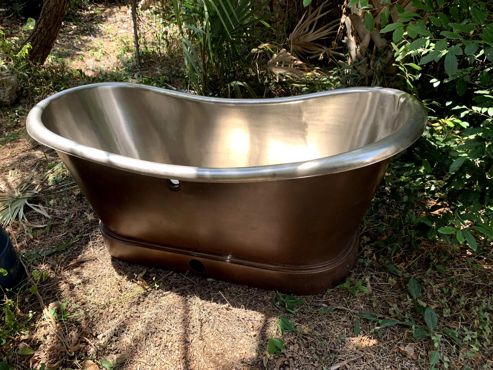 Copper slipper tub sitting outside, neglected, before refinishing