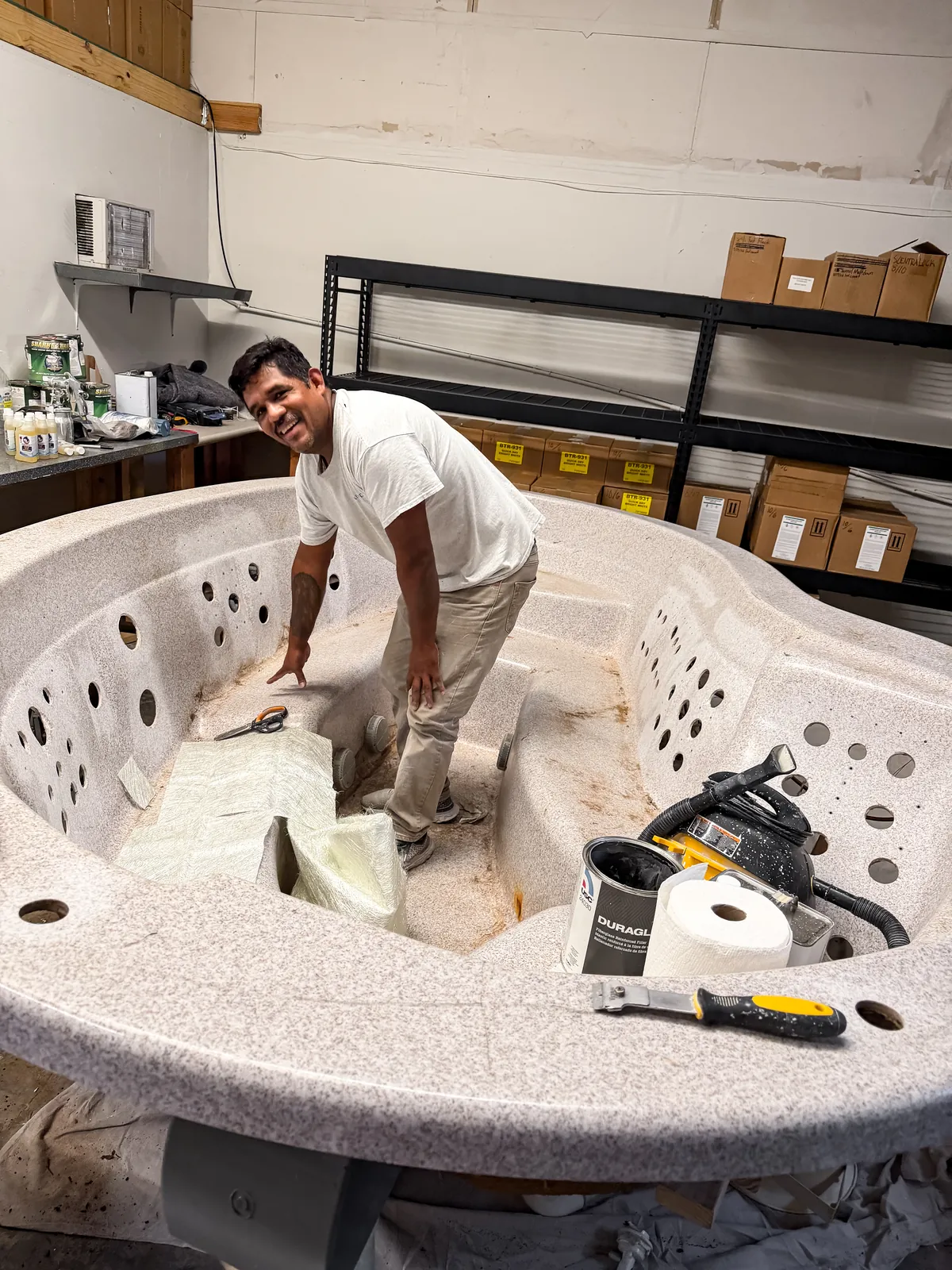 Technician stripping the old finish from the hot tub shell