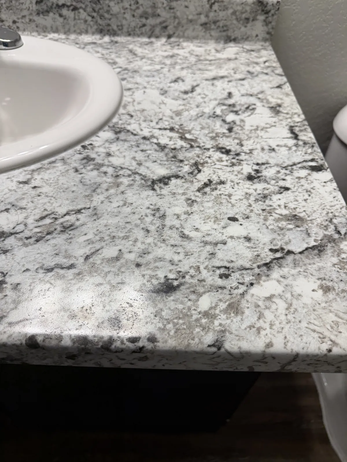 Apartment bathroom vanity with a granite-print laminate top, before